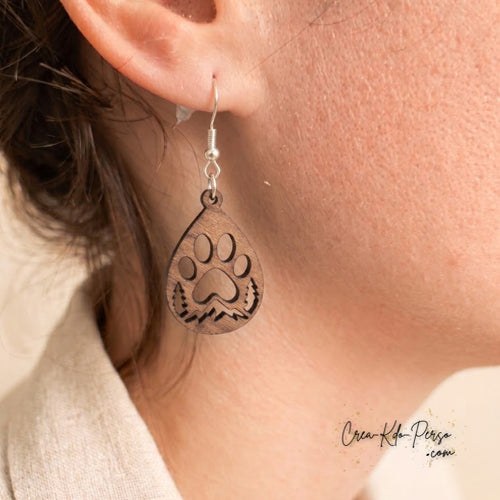 Boucle d'oreille en contreplaqué de bois découpée motif patte d'animal et forêt portée sur oreille